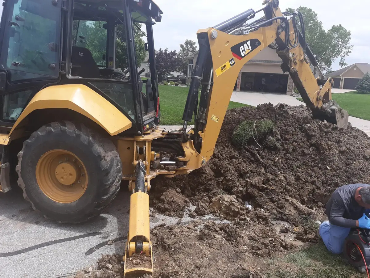 Excavation equipment beside an open underground plumbing work area